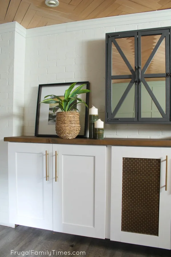 How to DIY a Media Cabinet Built-in - that looks great and hides everything! This media cabinet is made with prefab kitchen cupboards, custom doors and a chunky, natural, wood top. The decorative doors have a secret - you can use the remotes through the metal screen! custom entertainment center diy